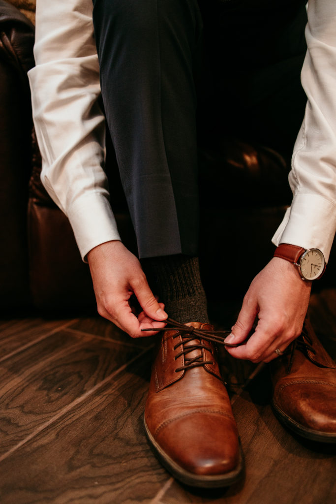 Groom carefully tying his shoes before marrying the love of his life