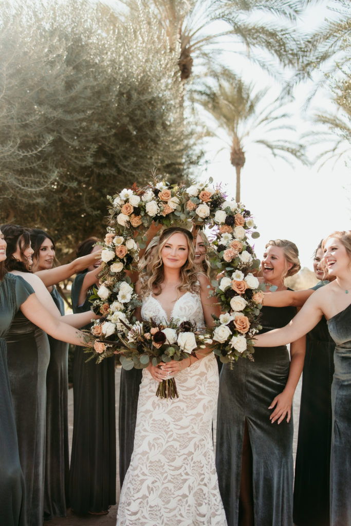 Blushing bride surrounded by her loving bridesmaids. bride is framed by her carefully chosen wedding flowers in the form of her bridesmaids bouquets
