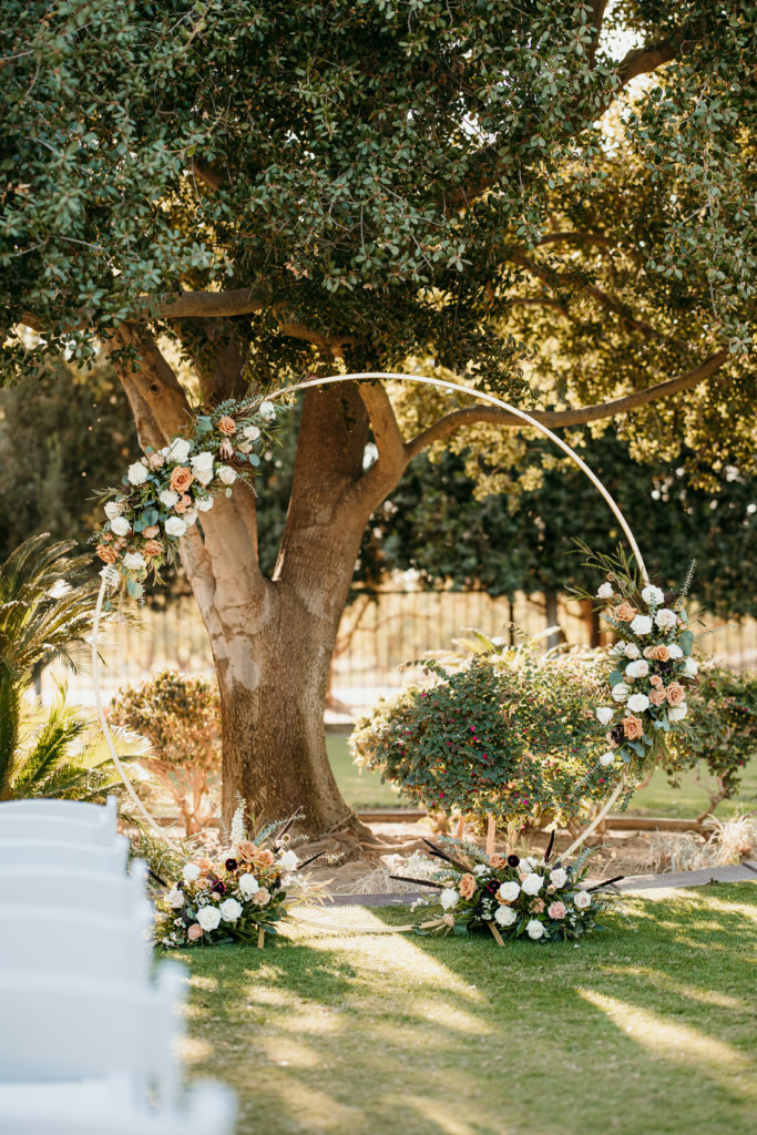 Round arch piece at the end of the aisle that is decorated with fresh blooms